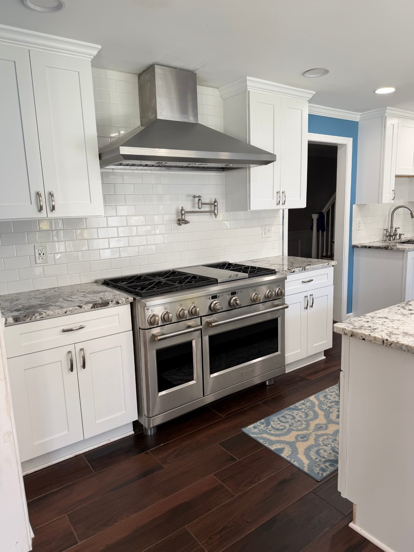 After kitchen renovation: professional stainless range with pot filler under a chimney hood