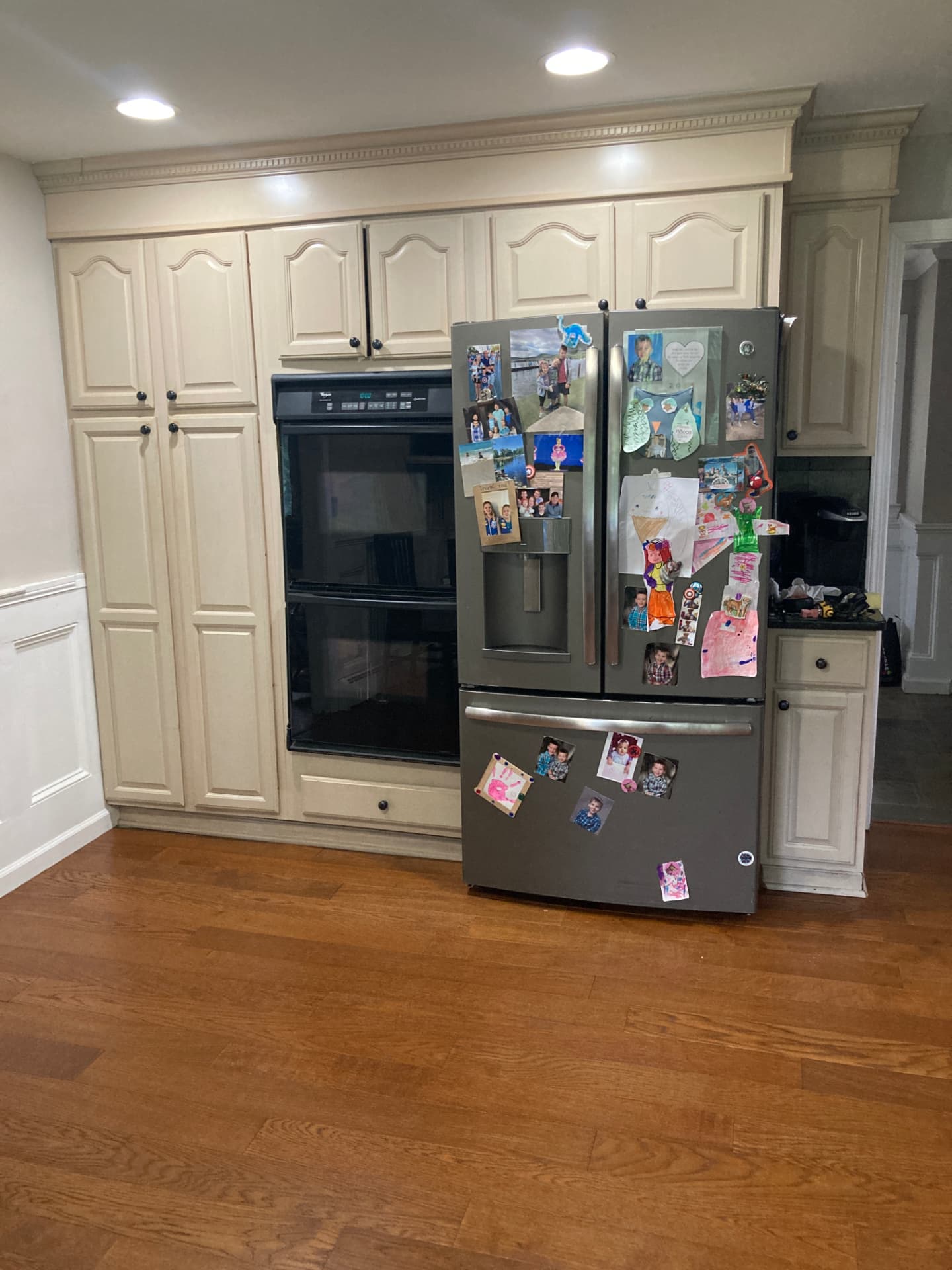 Before kitchen renovation: beige tall cabinets around the double oven and refrigerator