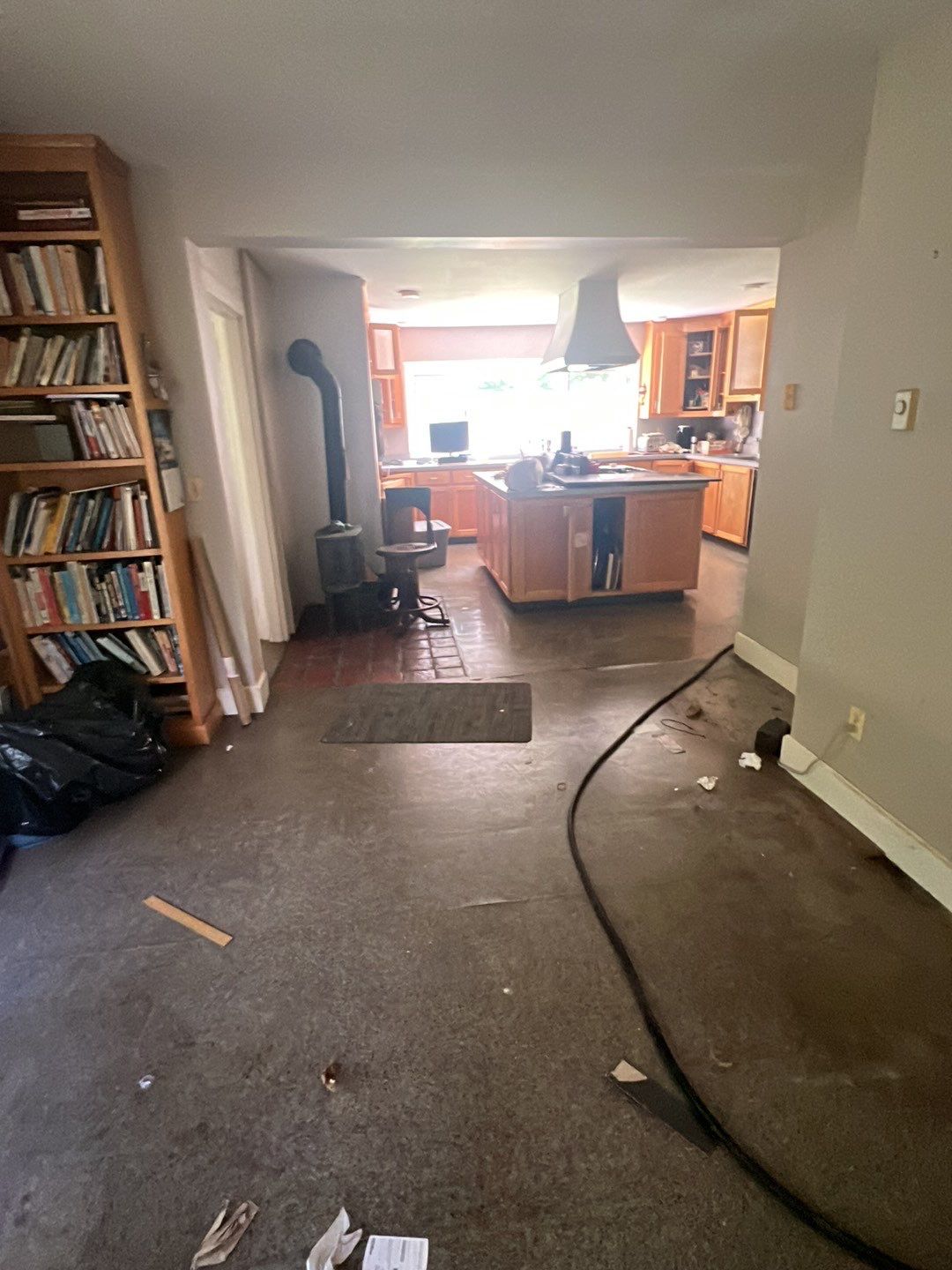 Before kitchen rebuild: honey-oak cabinets and island, worn floor and a black wood-burning stove by the window