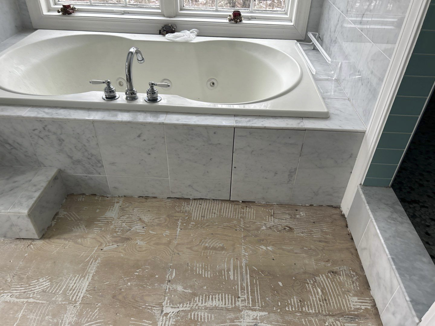 After bathroom work: built-in bathtub with tiled surround, with exposed flooring visible in front